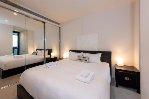 een slaapkamer met 2 bedden en een grote spiegel bij Stunning 1-bed Unit in 56th floor in Southbank! in Melbourne