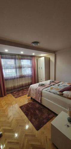 a bedroom with two beds and a wooden floor at Apartman Lux K in Bijeljina