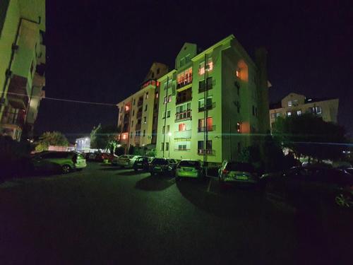 a building with cars parked in a parking lot at night at Apartman Lux K in Bijeljina