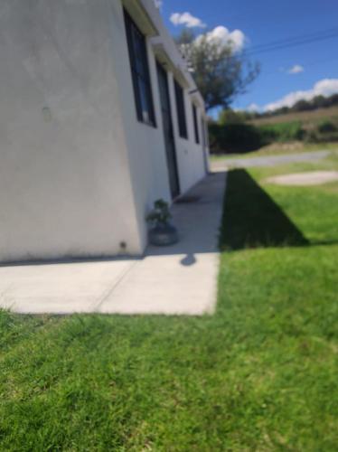 a white house with a porch and a grass yard at Posada Santa Elena in Santa María Atlihuetzián