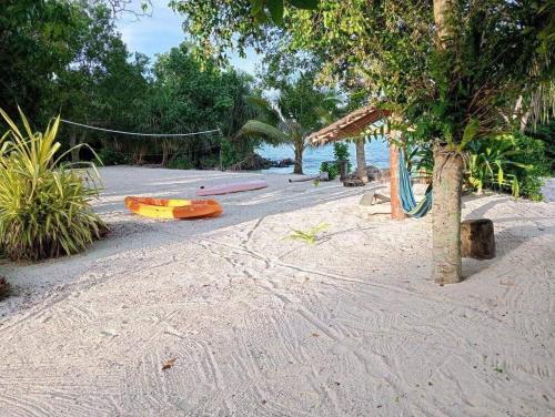 una playa con un parque infantil con un columpio en Hideaway Paradise Beach Bungalows, en Hog Harbour