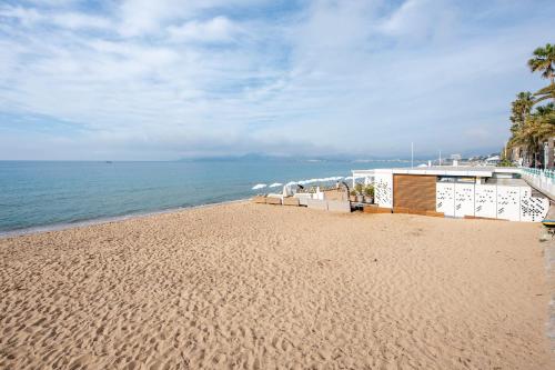 une plage de sable avec un bâtiment et l'océan dans l'établissement Appartement Dollia - Welkeys, à Cannes