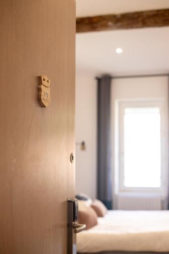 Cette chambre comprend un lit et une porte avec une étiquette sur le mur. dans l'établissement Hôtel d'Angleterre, Salon-de-Provence, à Salon-de-Provence