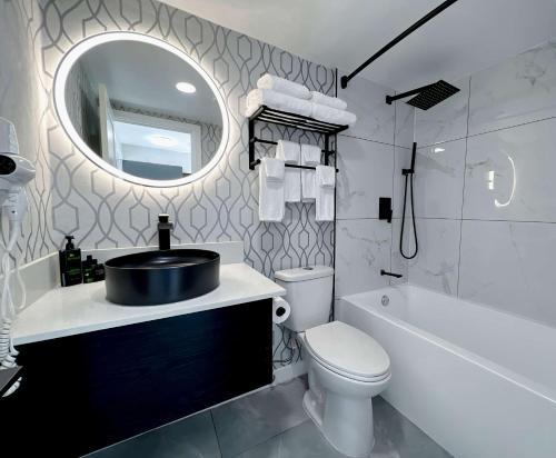 een badkamer met een wastafel, een toilet en een spiegel bij Coast Metro Vancouver Hotel in Burnaby