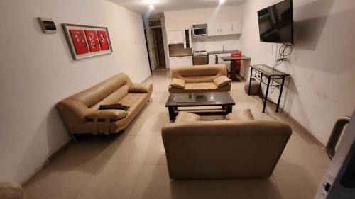 a living room with couches and a table and a tv at Departamentos en Playa Pulpos HOSPEDAJE DELFINES HOUSE in Lurín