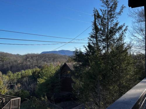 a house in the middle of a hill with a tree at Tranquility/Mountain Cabin/Indoor Pool/Hot Tub/Games/Views in Sevierville