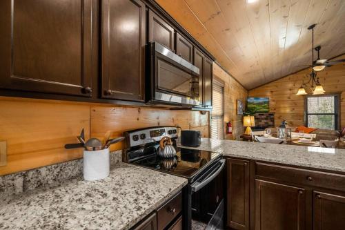 a kitchen with wooden cabinets and a stove top oven at Tranquility/Mountain Cabin/Indoor Pool/Hot Tub/Games/Views in Sevierville