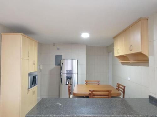 a kitchen with a table and a refrigerator at Apartamento Edificio Tuncahuan, 12 de octubre a 50mts Swissotel in Quito
