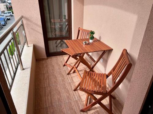 a wooden table and two chairs on a balcony at Апартаменти Bella Deluxe in Ravda