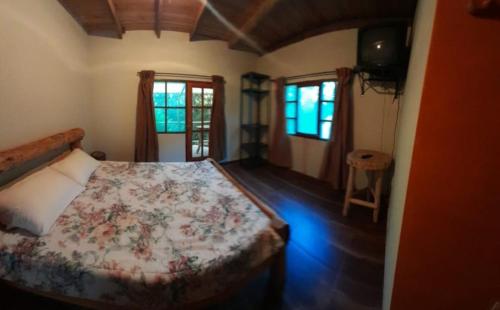 1 dormitorio con 1 cama con colcha de flores en Cabañas Campestres Villa Bella, en Coroico Viejo