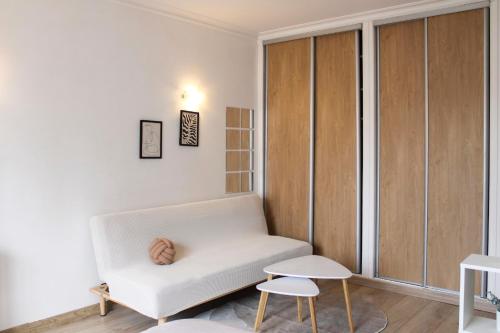 een woonkamer met een witte bank en 2 stoelen bij Cosy studio with balcony in Montreuil in Montreuil