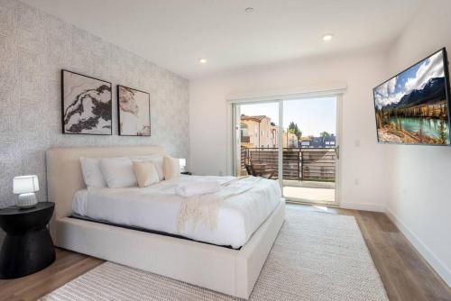 洛杉磯的住宿－Deluxe Modern 2-bedroom Condo w/ Roof Deck!，白色的卧室设有一张大床和一个窗户