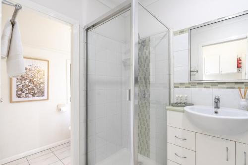a white bathroom with a shower and a sink at Bright & Cosy 1-Bed 15-Min From CBD in Brisbane