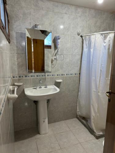 a bathroom with a sink and a shower with a mirror at Departamentos Malargue in Malargüe