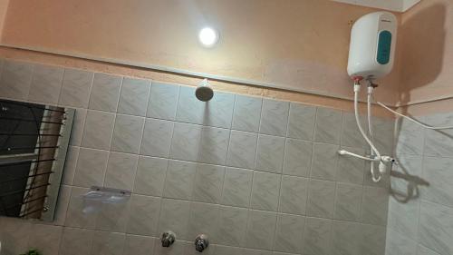 a shower in a bathroom with a hair dryer on the wall at Ka'vi in Dāvangere