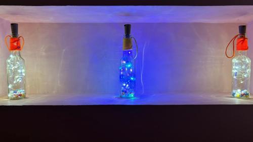 three glass bottles with lights in a room at Ka'vi in Dāvangere
