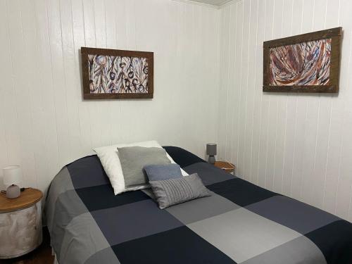 1 dormitorio con 1 cama y 2 cuadros en la pared en Hostel Cala 816 en Frutillar