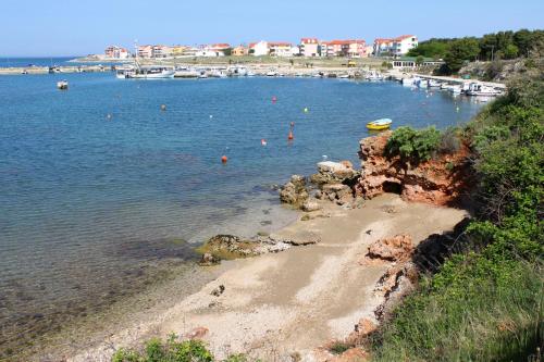 a beach with a bunch of boats in the water at Apartments and rooms with parking space Povljana, Pag - 22707 in Povljana