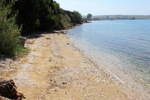 a sandy beach next to a body of water at Apartments and rooms with parking space Povljana, Pag - 22707 in Povljana