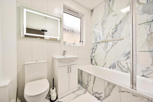 a white bathroom with a toilet and a sink at Luxury two bedroom a stride away from Meridian Greenwich in London