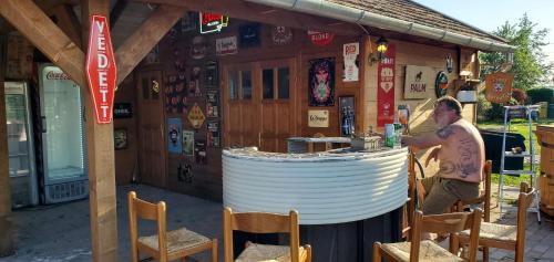 a man standing in front of a bar with chairs at Tiszaglamping, the belgian hideaway in Tiszacsege