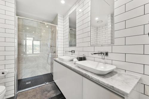 a white bathroom with two sinks and a shower at Stylish 2-Bed with Amenities 10-Min from CBD in Campbell