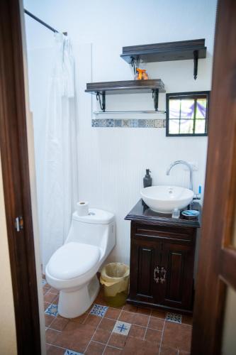 a bathroom with a white toilet and a sink at Hotel Taa' Tiin in San Juan La Laguna