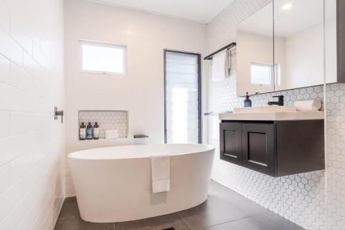 uma casa de banho branca com uma banheira e um lavatório em 'The Otto' At Moffat Beach em Caloundra