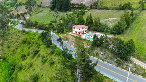 a house on the side of a hill next to a road at Hostal El Inca in Chucchilán