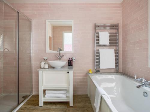 a pink bathroom with a tub and a sink at The Hedgehog-uk46923 in Newby Bridge