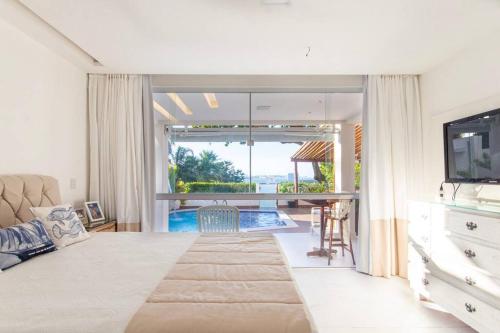 a bedroom with a large bed and a living room at Casa em resort, beira mar, 4 suítes, piscinas in Parnamirim