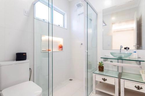 a bathroom with a glass shower and a sink at Casa em resort, beira mar, 4 suítes, piscinas in Parnamirim