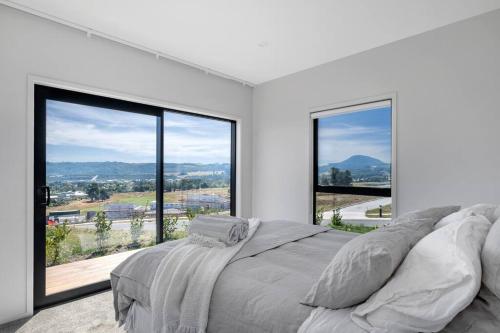 a bedroom with a large bed and large windows at Kinloch Bach with heaps of room! in Kinloch