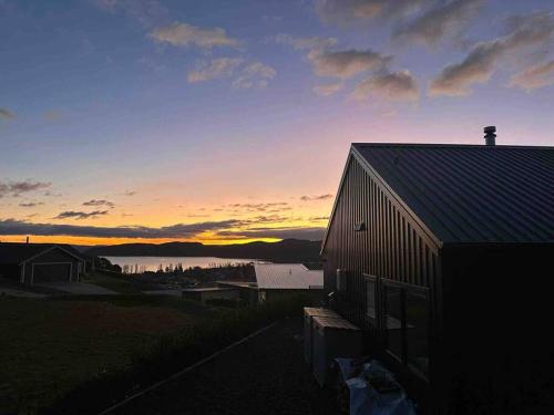 a sunset over a barn and a body of water at Kinloch Bach with heaps of room! in Kinloch
