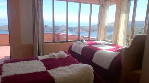two beds in a room with a large window at Inti kala lodge in Comunidad Yumani