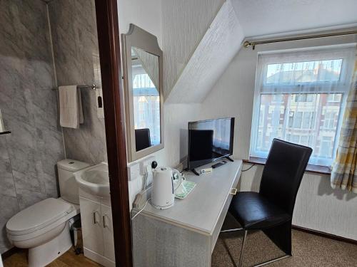 a bathroom with a toilet and a desk with a computer at Collingwood Hotel in Blackpool
