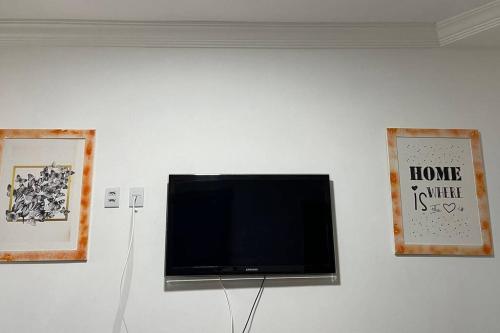 TV de pantalla plana en una pared con 2 imágenes en Apartamento Salvador/200m da praia., en Salvador