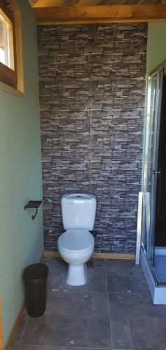 a bathroom with a toilet in front of a brick wall at Tiszaglamping, the belgian hideaway in Tiszacsege
