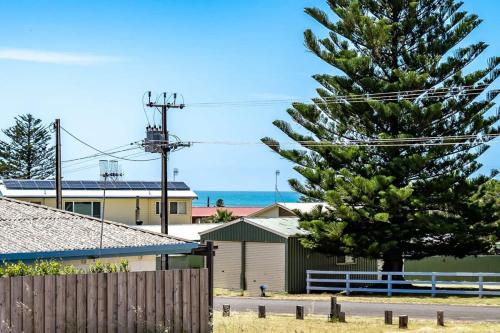 a pine tree in front of a house and a fence at 11 Elizabeth - BYO Linen - Ocean Glimpses in Middleton