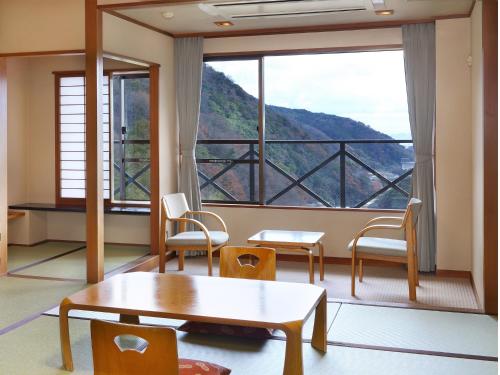 a room with a table and chairs and a large window at Hakonenomori Okada in Hakone