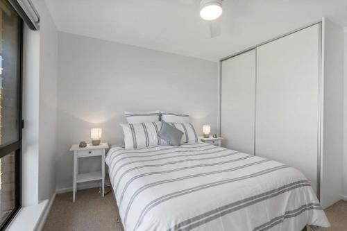 a white bedroom with a large bed and two lamps at 11 Elizabeth - BYO Linen - Ocean Glimpses in Middleton