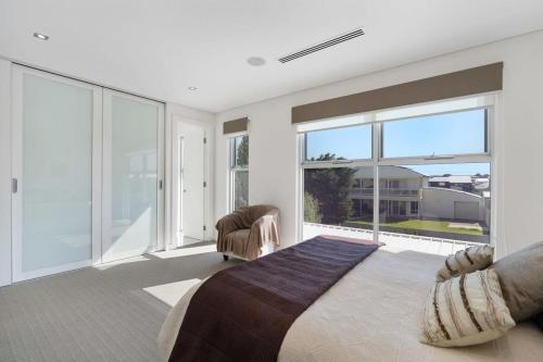 um quarto com uma cama grande e janelas grandes em 52 Esplanade - BYO Linen - Luxury - Seafront - Wi-Fi em Middleton