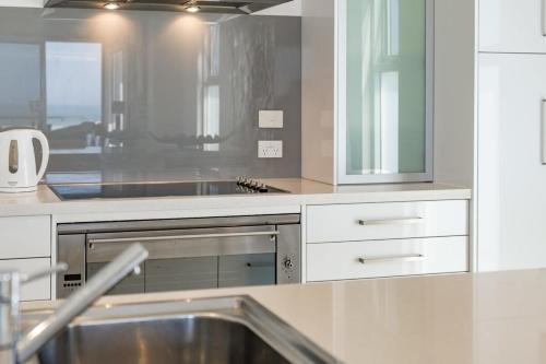 uma cozinha com um lavatório e uma bancada em 52 Esplanade - BYO Linen - Luxury - Seafront - Wi-Fi em Middleton