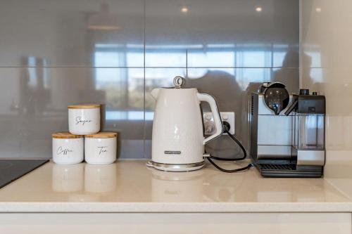 a coffee maker and three cups on a kitchen counter at Hindmarsh Island Marina Lifestyle - BYO Linen in Hindmarsh Island