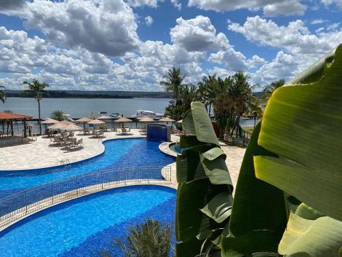 a resort swimming pool with a view of the water at Luxuoso flat familiar beira lago in Brasilia