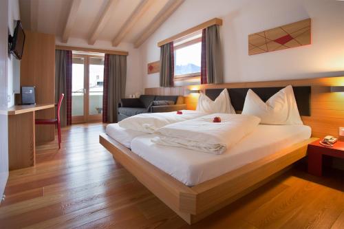 a bedroom with a large bed with white sheets at Hotel Al Cervo in Tesero