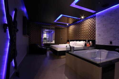 a bathroom with a tub and a bed with purple lights at Motel Deslize Limeira 5 in Limeira