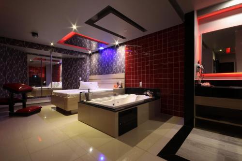 a bathroom with a tub and a bed in a room at Motel Deslize Limeira 5 in Limeira