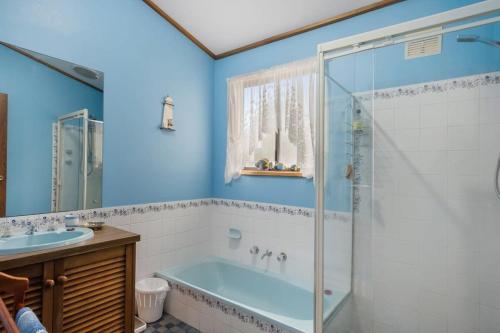 La salle de bains bleue est pourvue d'une baignoire et d'un lavabo. dans l'établissement Cave Street Retreat - 38 Cave Street Goolwa Beach - BYO Linen, à Goolwa South