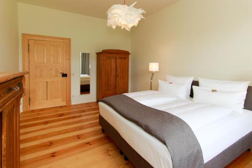 a bedroom with a large white bed and a chandelier at Ferienwohnungen Bahnhof Werder in Jüterbog